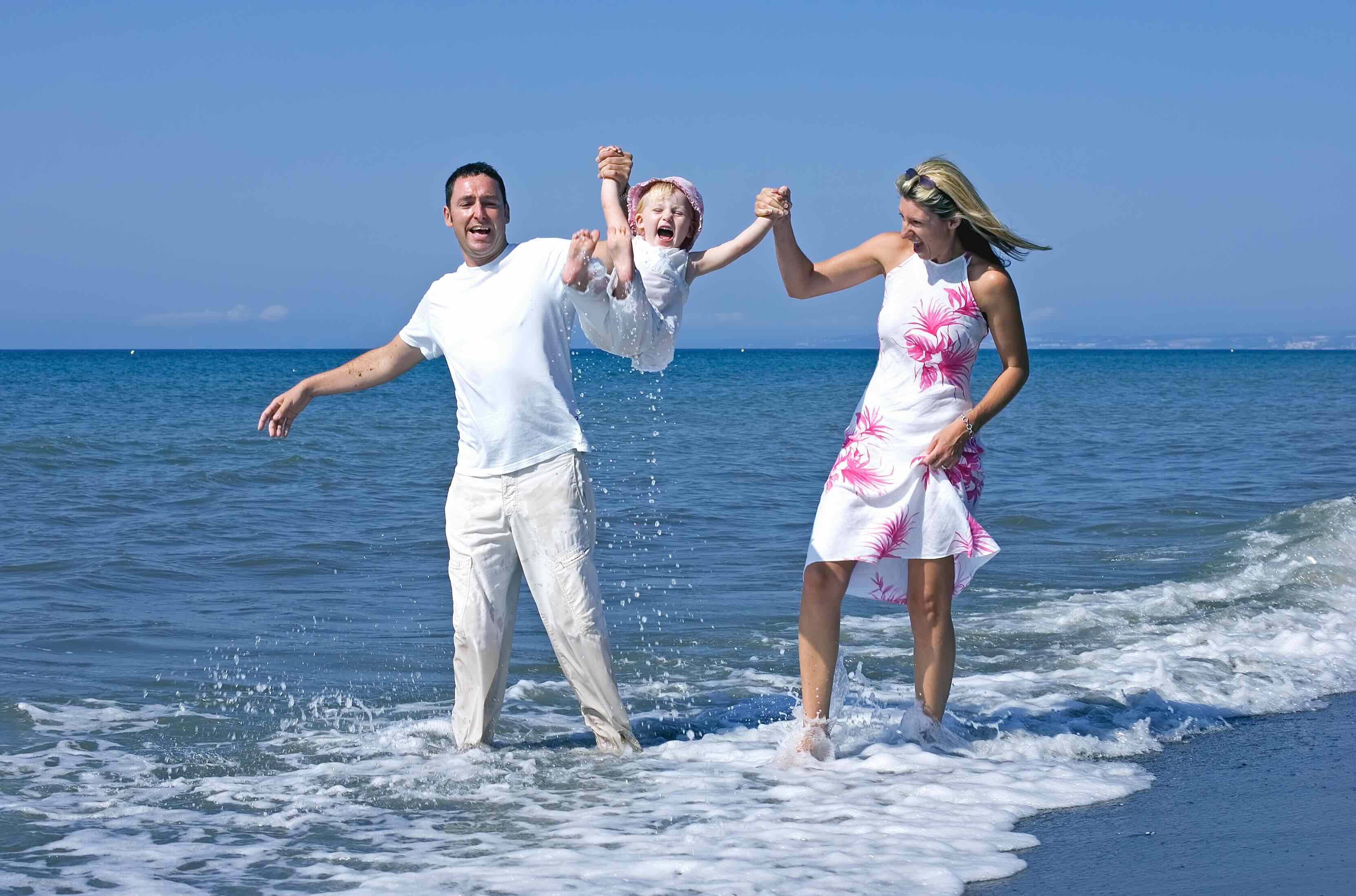 Familie am Strand wirft ihr Kind lachend in die Luft